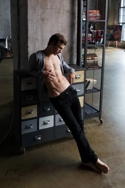 Gömleksiz yakışıklı genç kumral onun altı paketi IAT profesyonel bir photostudio bir trendy hipster iç gösteriler bir çekmece yaslanmış