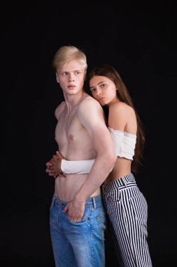 Genç ve güzel çift. Sarışın erkek ve hafif kahverengi kız. Kız bir adam etrafında kollarını sarılmış. Gömleksiz. Uygun. Ciddi ve romantik. 