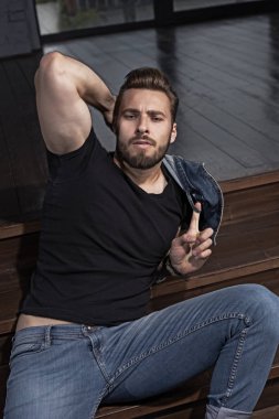 Kahverengi saç ve sakal ahşap merdivenlerinde oturmuş olan yakışıklı maço adam