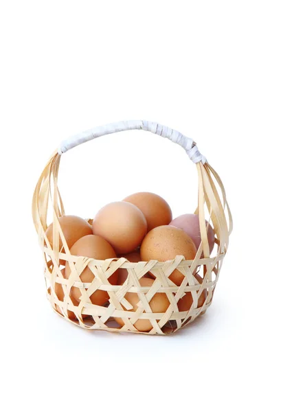 Свежие яйца в круглой бамбуковой корзине, изолированной дорожкой . Стоковая Картинка