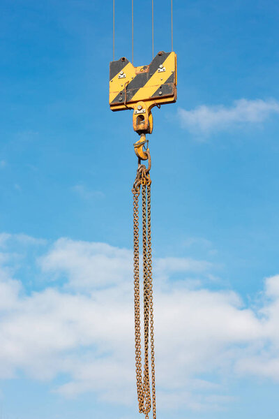Crane load hook against the sky with trails and chain.
