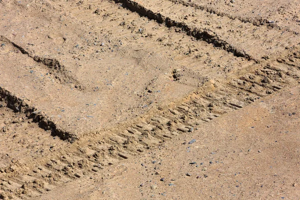 Traces of tire treads on a dry soil surface.