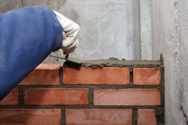 Bir mala ile El, kırmızı tuğla bir duvar döşeme sürecinde
