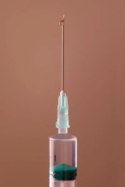 The end of the syringe with a needle filled with liquid, on a ne — Stock Photo, Image