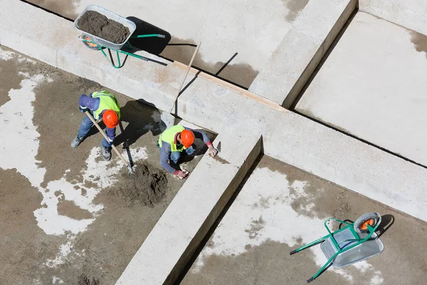 Uniformed workers clean sand on a construction site, top view. — Stock Photo, Image