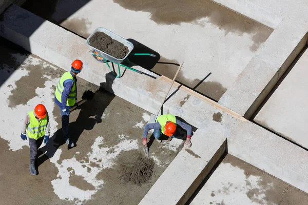 Uniformed workers clean sand on a construction site, top view. — Stock Photo, Image