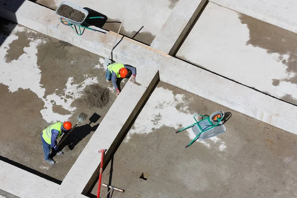 Uniformerade arbetare ren sand på en byggarbetsplats, ovanifrån. — Stockfoto