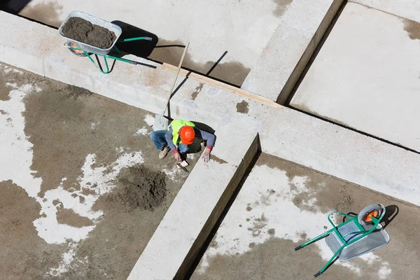 Des ouvriers en uniforme nettoient le sable sur un chantier, vue de dessus. — Photo