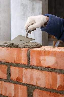 Bir mala ile El, kırmızı tuğla bir duvar döşeme sürecinde