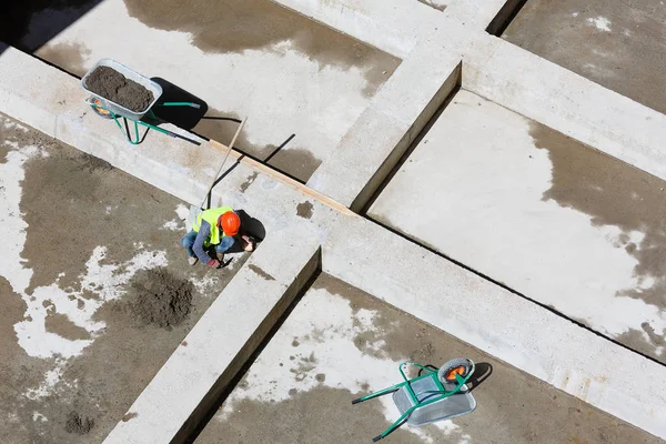 제복을 입은 일꾼들이 건축 현장에서 모래를 청소하는 모습, 맨 위에서 본 광경. — 스톡 사진