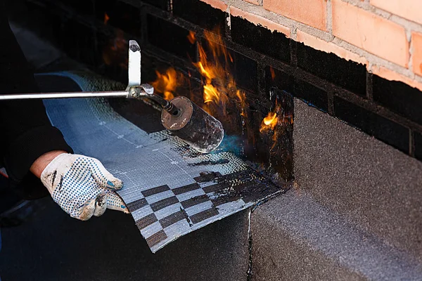 Verlegung von Abdichtungen durch Erhitzen von Dachfilz mit Feuer. — Stockfoto