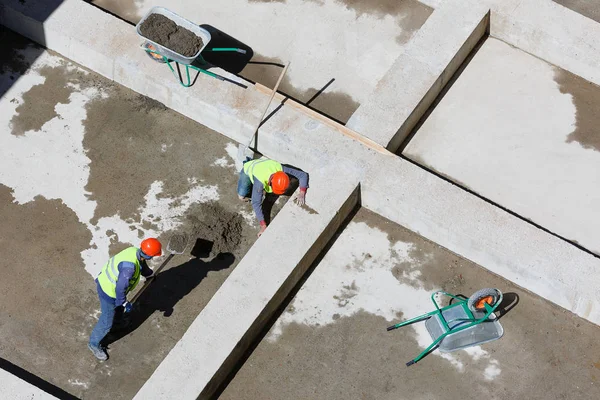 Uniformed workers clean sand on a construction site, top view. — Stock Photo, Image