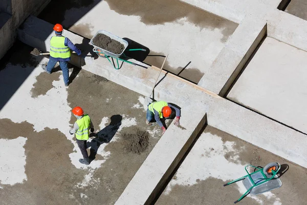 Uniformed workers clean sand on a construction site, top view. — Stock Photo, Image