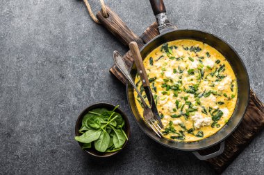 Ispanak ve peynirli beton arka plan üstten görünüm üzerinde bir tavada omlet
