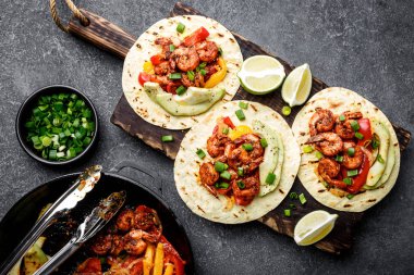 Düz fajitas ekmeği Kızarmış karides, biber ve soğan üzerinde ahşap kesme tahtası, üstten görünüm, avokado ve yeşil soğan ile servis içinde yatıyordu