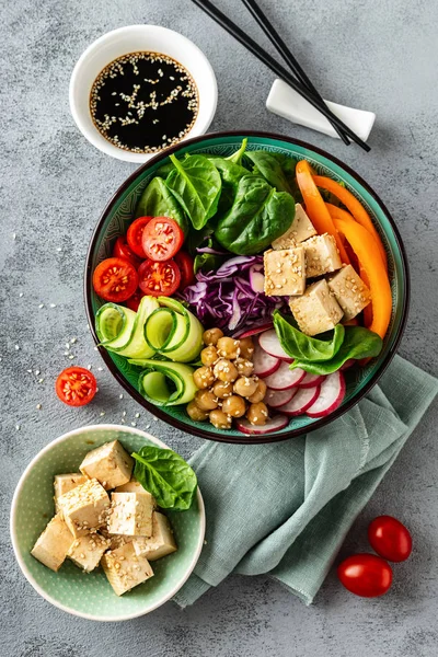 Buddha bowl salad with chickpeas, sweet pepper, tomato, cucumber, red cabbage kale, fresh radish, spinach leaves and tofu cheese, healthy balanced clean eating concept, top view, flat la