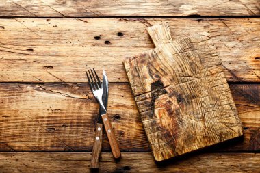 Gıda arka plan, boş kesme tahtası bir bıçak ve çatal bir rustik ahşap masa, üst görünümü ile servis