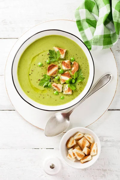 Pea soup. Green pea puree soup in a bowl served with grilled toasts, top view