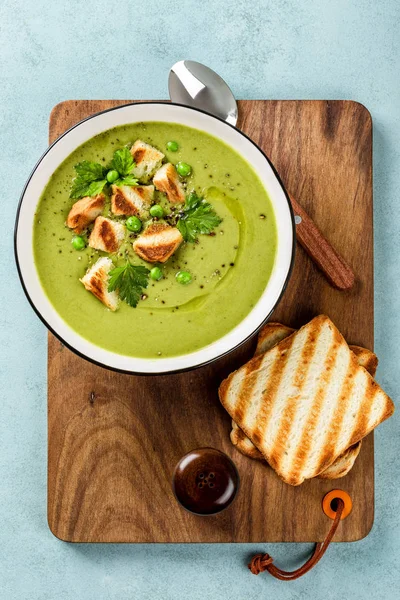 Pea soup. Green pea puree soup in a bowl served with grilled toasts, top view