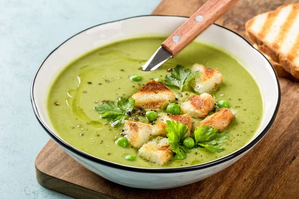 Pea soup. Green pea puree soup in a bowl served with grilled toasts, top view