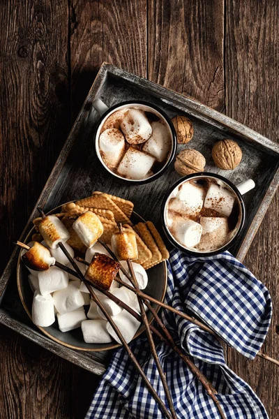 ホットチョコレートやココアドリンクやマシュマロなど素朴な木のテーブルの上で提供されるお菓子 — ストック写真