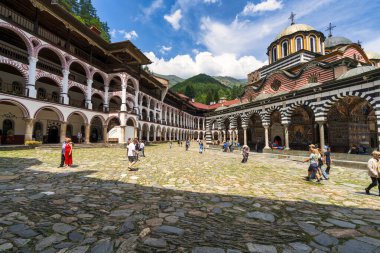 Rila Manastırı, Bulgaristan - 6 Ağustos 2025: Bulgaristan 'ın Rila Manastırı' nın avlusunda yürüyen ziyaretçiler, dağlarla çevrili bir UNESCO Dünya Mirası Alanı ve tarihi mimariyle çevrili.