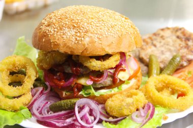 Burger kırmızı soğan, kaşar peyniri, kızarmış halkalar ve dekapaj salatalık. Portre. Fast food Restoran, yemek festivali kavramı