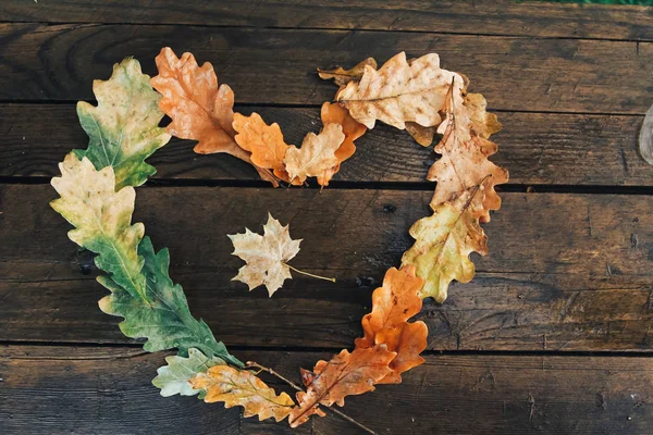 Maple leaf in heart. Fall leaves heart frame with on wooden desk. Autumn background concept. Oak planks, raining, September, October, November, thanksgiving, top view