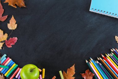 Renkli kalemler, defter, boya kalemi, yeşil elma ve sonbahar tahta üzerinde yaprakları. Üst görünüm, kopya alanı, Clack, çerçeve, sınır. Eğitim, sonbahar, okul konseptine geri dön