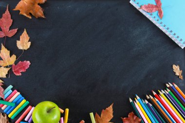 Renkli kalemler, defter, boya kalemi, yeşil elma ve sonbahar tahta üzerinde yaprakları. Üst görünüm, kopya alanı, Clack, çerçeve, sınır. Eğitim, sonbahar, okul konseptine geri dön