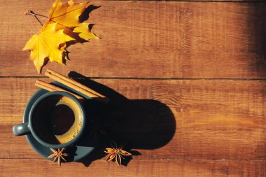 Gri bir fincan kahve, tarçın, koyu ahşap masa üzerinde sarı akçaağaç yaprakları. Sonbahar arka plan konsepti. Sonbahar menüsü, expresso, kafe, mola, kopya alanı, sayfa, üst görünüm