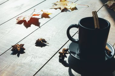 Gri fincan kahve, tarçın çubuğu, tahta masaüzerinde sarı ve kırmızı akçaağaç yaprakları. Sonbahar konsepti. Sonbahar menüsü, expresso, kafe, mola, kopya alanı, sayfa, üst görünüm