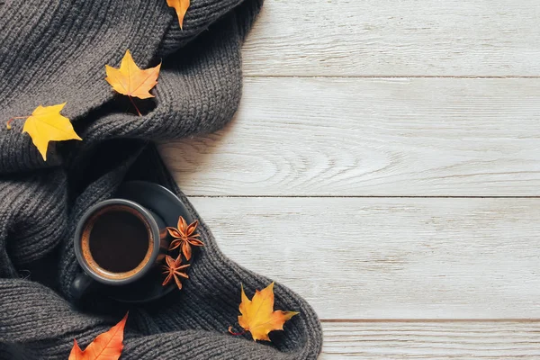 Grey cup of coffee, yellow fall leaves, scarf  on white wooden table. Autumn background concept. Fall menu, expresso, coffee shop, break, copy space, page