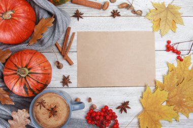 Baharatlı kahve fincanı, ekose ya da eşarp, sarı yapraklar, balkabakları, beyaz ahşap masadaki boş kağıt. Sonbahar içkisi konsepti. Sonbahar, baharatlı latte, şükran günü, top, kopyalama alanı