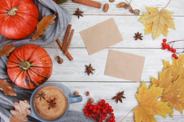 Baharatlı kahve fincanı, ekose ya da eşarp, sarı yapraklar, balkabakları, beyaz ahşap masadaki boş kağıt. Sonbahar içkisi konsepti. Sonbahar, baharatlı latte, şükran günü, top, kopyalama alanı
