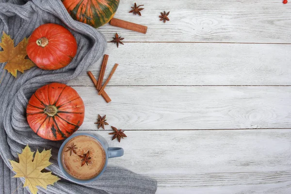 Grey cup, plaid or scarf, orange pumpkins, spices, yellow maple leaves on white wooden table. Autumn drink concept. Fall, pumpkin spicy latte, thanksgiving, top, copy space