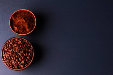 Kil kaselerde kavrulmuş fasulye ve koyu mavi masa arkaplanı. Yakın çekim, üst görüntü, kopyalama alanı. Kahve dükkanı, sabah, baristaların işyeri konsepti.