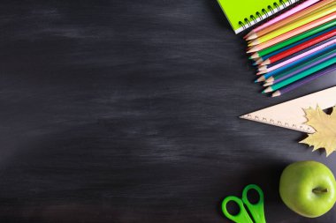 Renkli kalem, yeşil elma, sonbahar yaprağı, karatahta desenli okul malzemeleri. Üst görünüm, kopyalama alanı, düz yatış. Sonbahar konseptiyle okula dönüyorum.