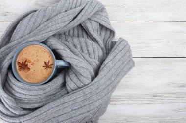 Yün atkı ya da ekoseye sarılı baharatlı gri kahve kupası. Sonbahar veya kış içeceği konsepti, Latte, cappuccino, Ekim, Kasım, anason