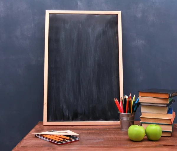 School desk. Green apples, books, pencils pot, blackboard in frame on wooden brown table. Copy space, close-up. Back to school, organic food concept