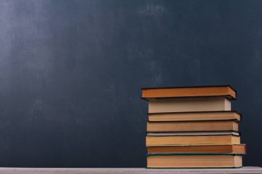 Lacivert duvar arkaplanına karşı beyaz ahşap masadaki kitap yığını. Yan görüş, kopyalama alanı, yakın çekim. Öğrenme, eğitim, bilgi, kütüphane, aşk okuma kavramı