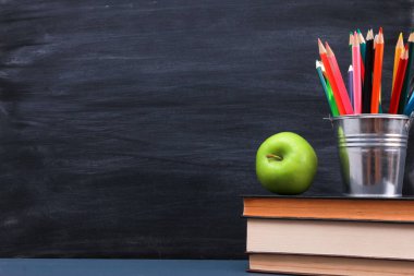 Koyu mavi masadaki koyu renkli kalemler. Arkaplanda tebeşir çizgileri olan karatahta desenli. Yakın çekim, kopyalama alanı. Okul konseptine dönelim.