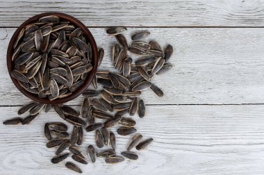 Ayçiçeği tohumları beyaz ahşap masaya saçılmış vaziyette. Üst görünüm, yakın çekim, kopyalama alanı. Gıda, hasat, tarım, tarım kavramı