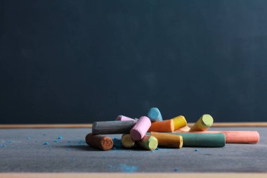 Tahtada kırıntılar olan renkli tebeşir parçaları yığını. Yan görüş, kopyalama alanı, yakın çekim. Okula dönüyorum, çizim konsepti.