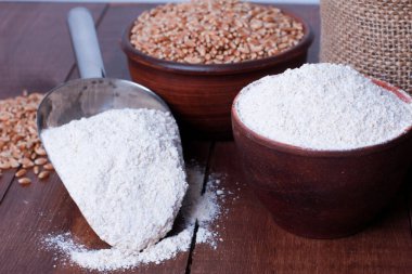 Kâsede kepçe kepçe un tozu, kahverengi ahşap masada tahıl çuvalı. Yüksek açı, yakın çekim. Hasat, yemek, malzeme, pişirme konsepti