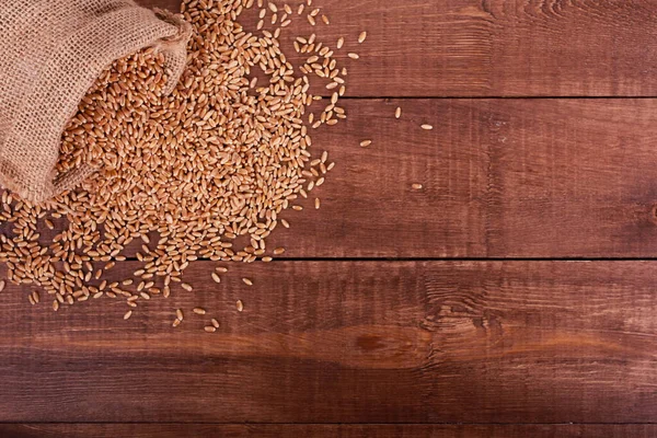 Stapel Van Gouden Tarwekorrels Verspreid Uit Jute Zak Bruine Houten — Stockfoto