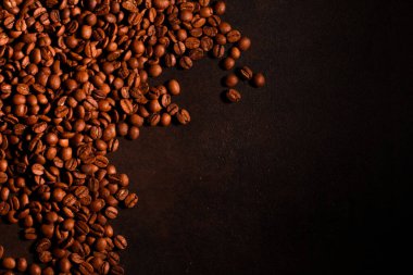 Koyu arkaplanda doğal kahve çekirdekleri yığını. Kavrulmuş Arap tohumları kenar kenarı, kopyalama alanı, üst görünüm. Kahve dükkanı, kafein, rosto konsepti.