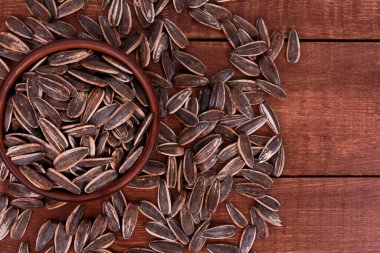 Kahverengi ahşap masadaki kasede ayçekirdeği tohumu yığını. Üst manzara, yakın çekim. Gıda, hasat, tarım, tarım kavramı