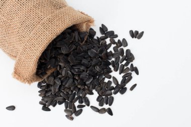 Çuvaldan yayılmış ayçekirdeği yığını. Üst görünüm, beyaz arkaplanda izole nesne. Gıda, hasat, tarım, tarım kavramı