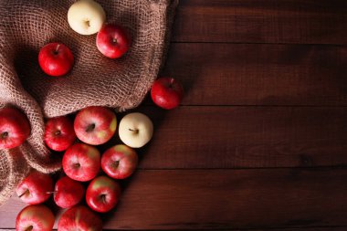 Kırmızı taze elmalar, kahverengi tahta üzerinde çuval bezi. Üst görünüm, boşluğu kopyala. Doğal organik gıda, tarım, bahçıvanlık, hasat mevsimi konsepti